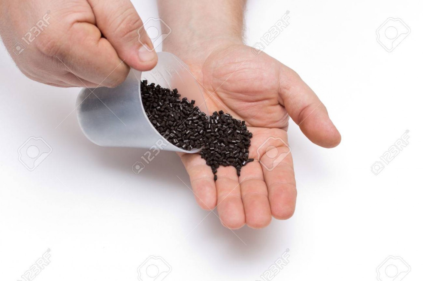 Plastic pellets spilled out of the measuring Cup on a man's hand